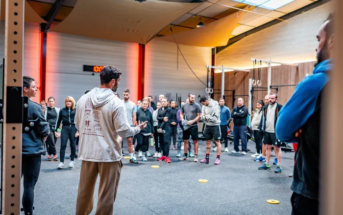 Un coach du Côtière Sport Club explique le WOD du jour à un groupe de membres réunis en cercle dans la box